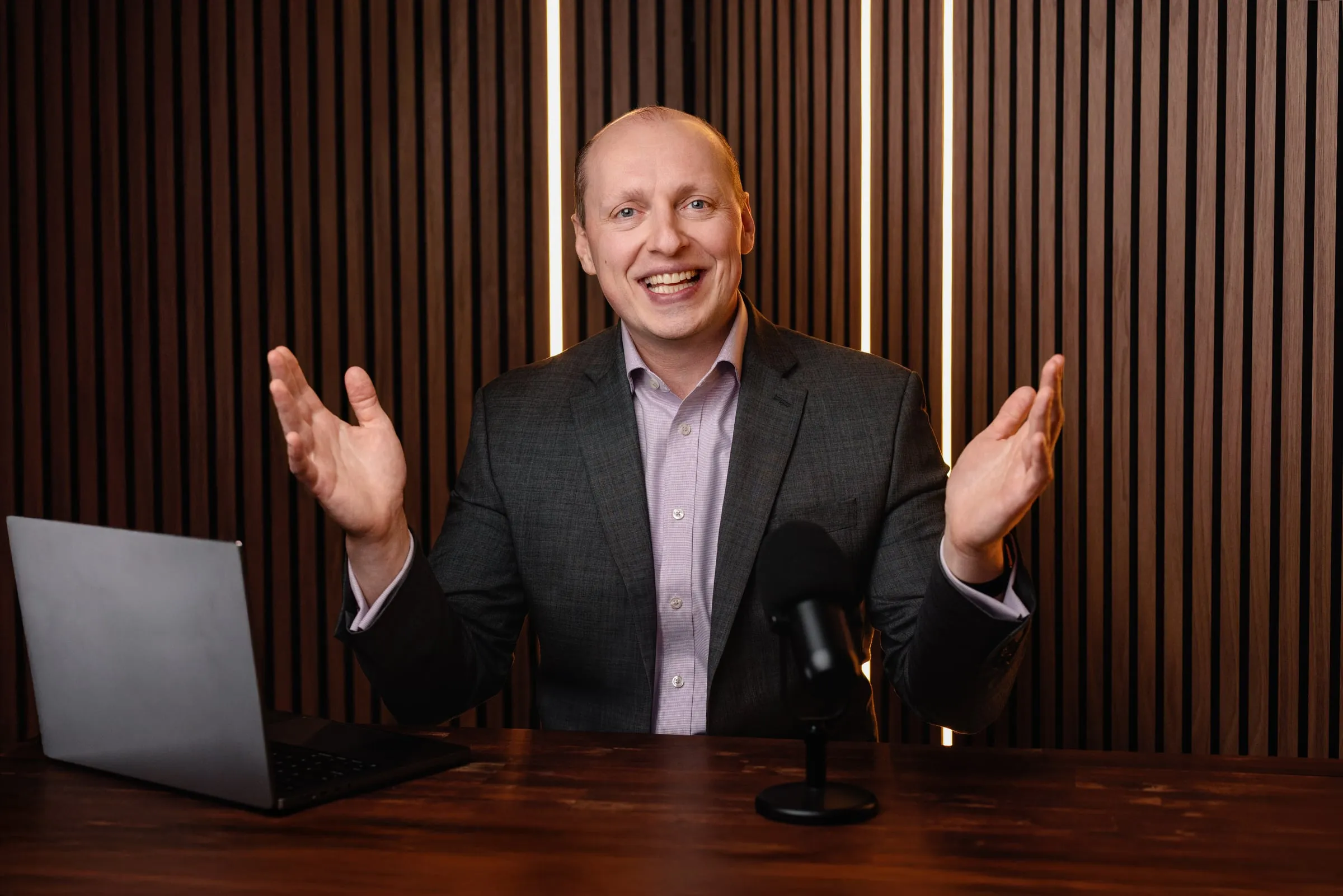 Yuriy Demidko at a podcast desk, laughing with both hands open
